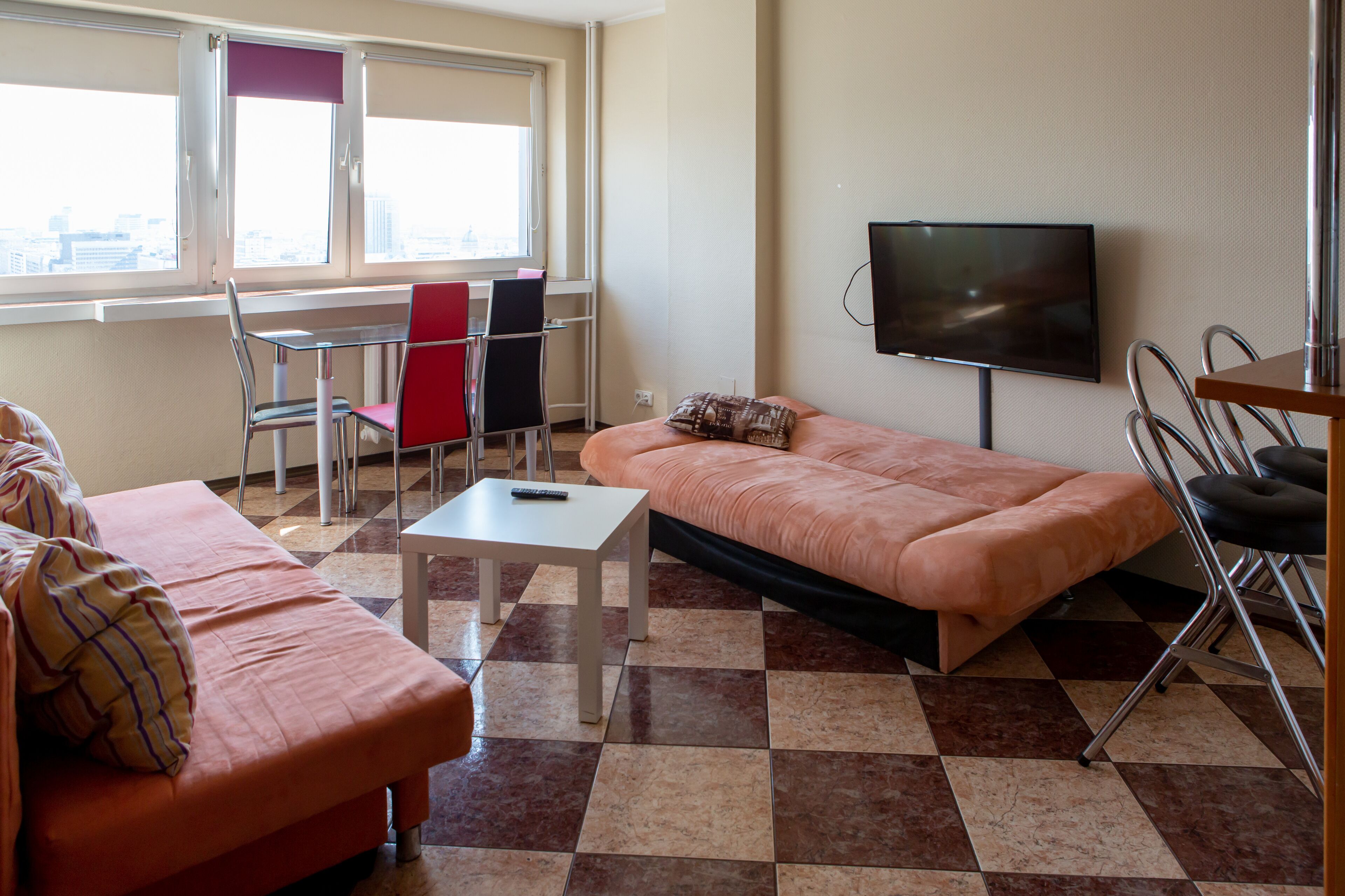 Un salón amueblado con sofá, una mesita, televisor y ventana con vista a la ciudad.