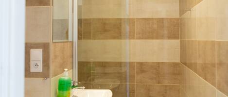 A bathroom with a glass shower enclosure, a sink, and a toilet.