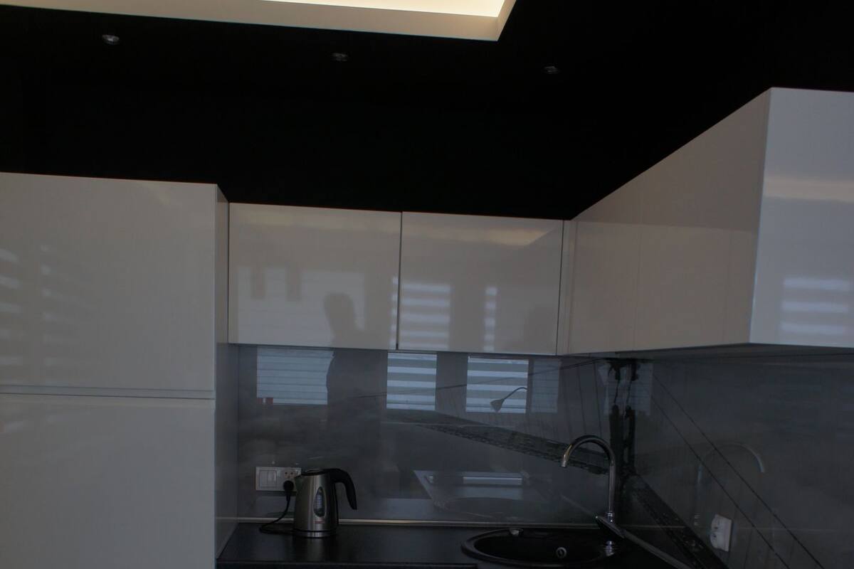 A modern kitchen with white cabinets, a black countertop, and a checkered floor.