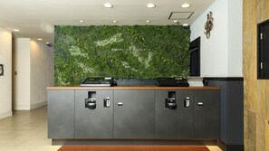 Una reception con parete verde, televisore a schermo piatto e bancone in legno.