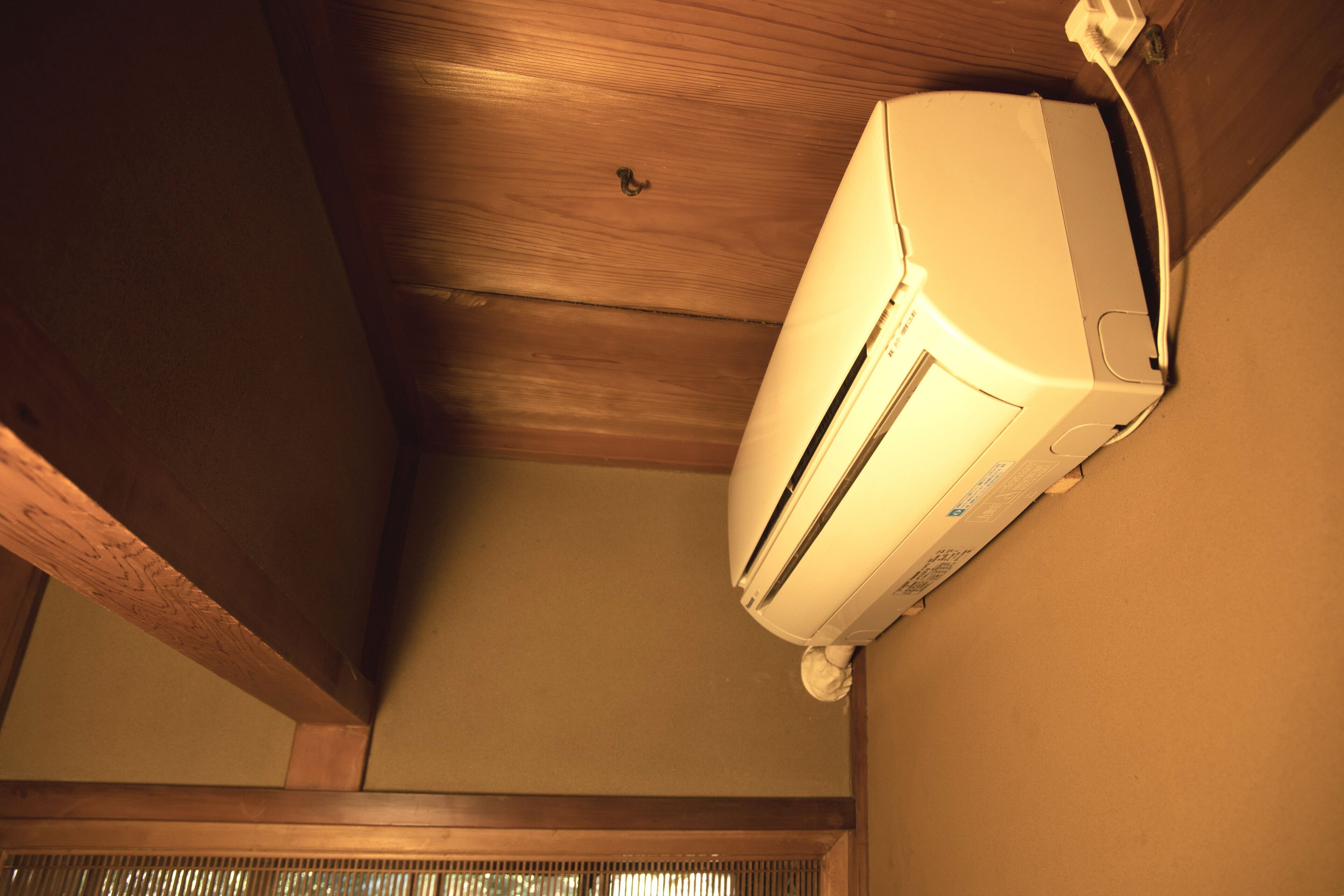 A ceiling with a white air conditioning unit mounted on a wall.