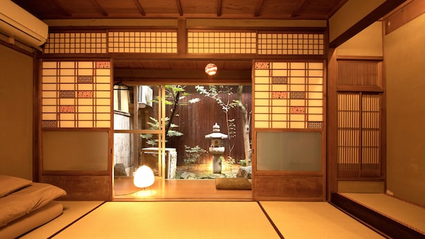 A traditional Japanese room with tatami flooring, sliding doors, and a view of a garden with a stone lantern. - Guesthouse YULULU (Kyoto)