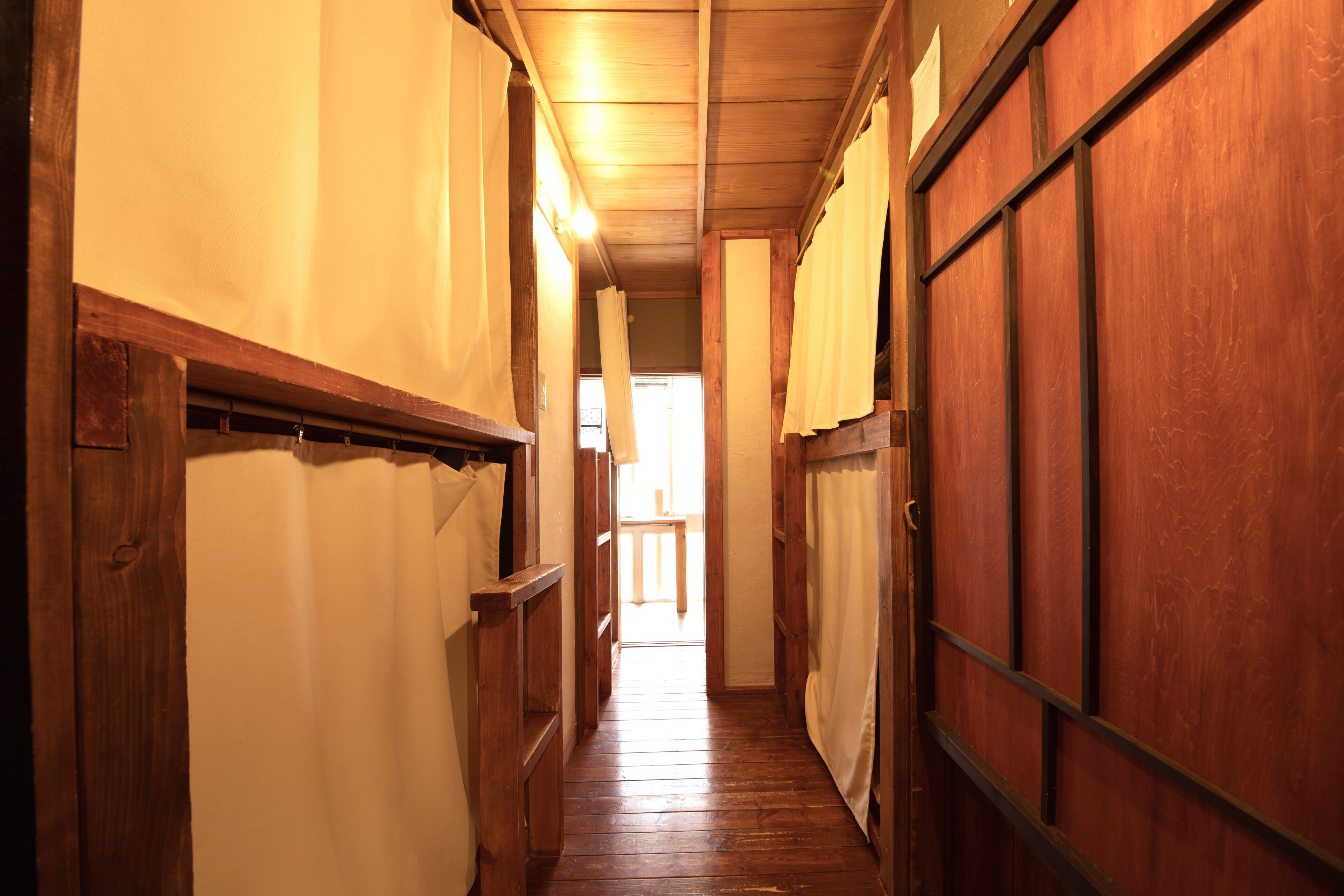 A narrow wooden hallway with a wooden door at the end.
