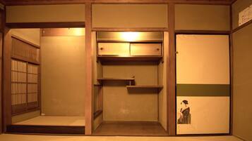 A traditional Japanese room with tatami flooring, a sliding door, a built-in shelf, and a small alcove with a picture.