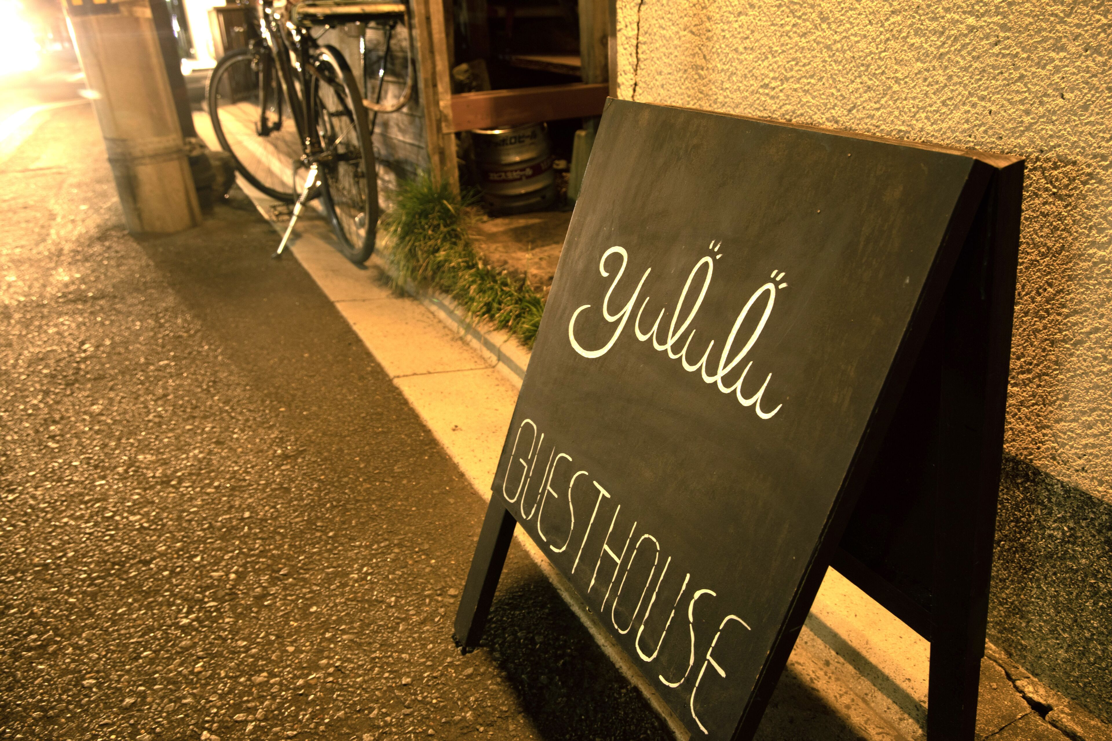 Un cartel con la palabra 'Yulii' y 'POSADA' escrito, colocado en una acera al lado de un edificio.
