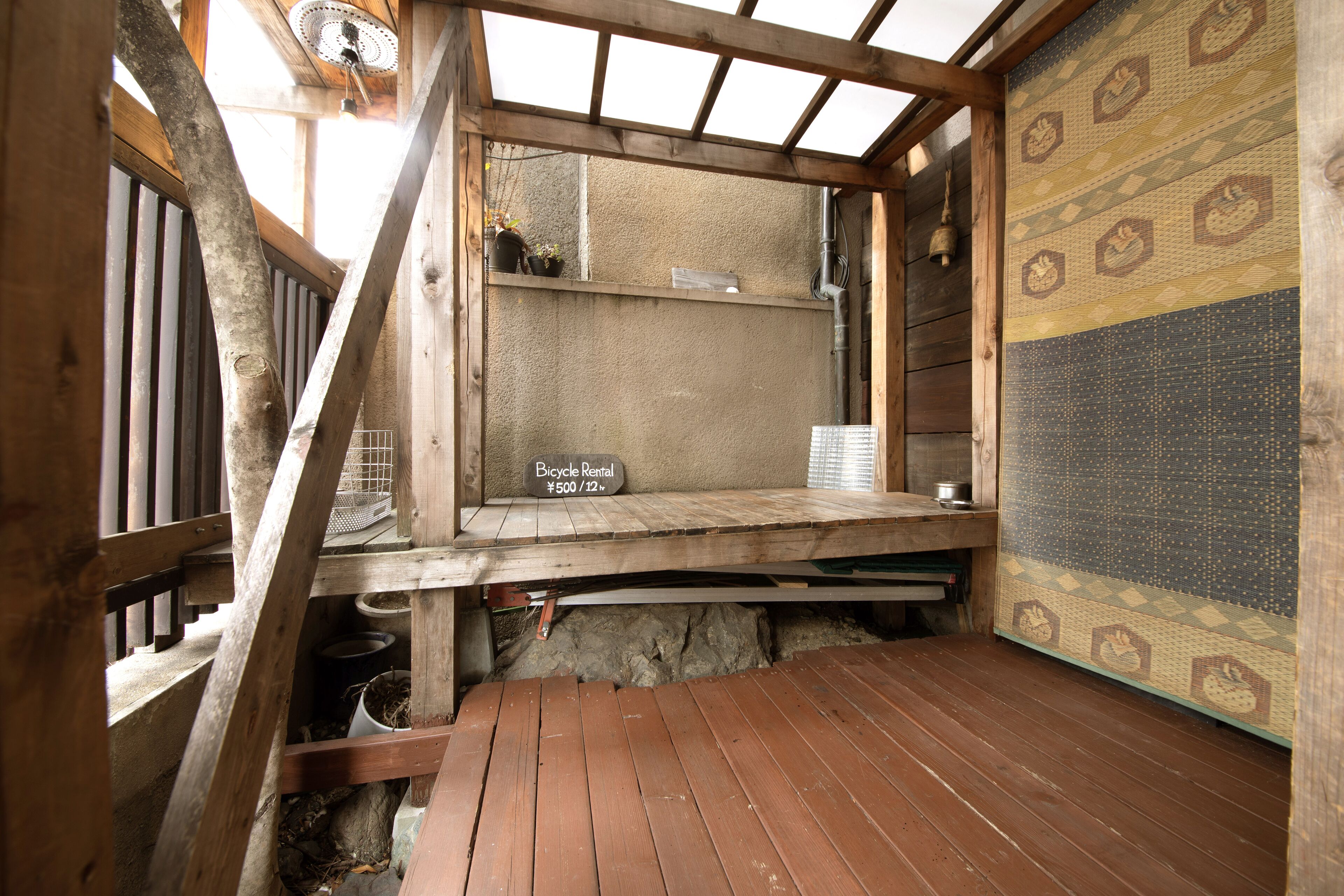 A wooden room with a bicycle rental sign, a wooden bench, and a patterned wall.
