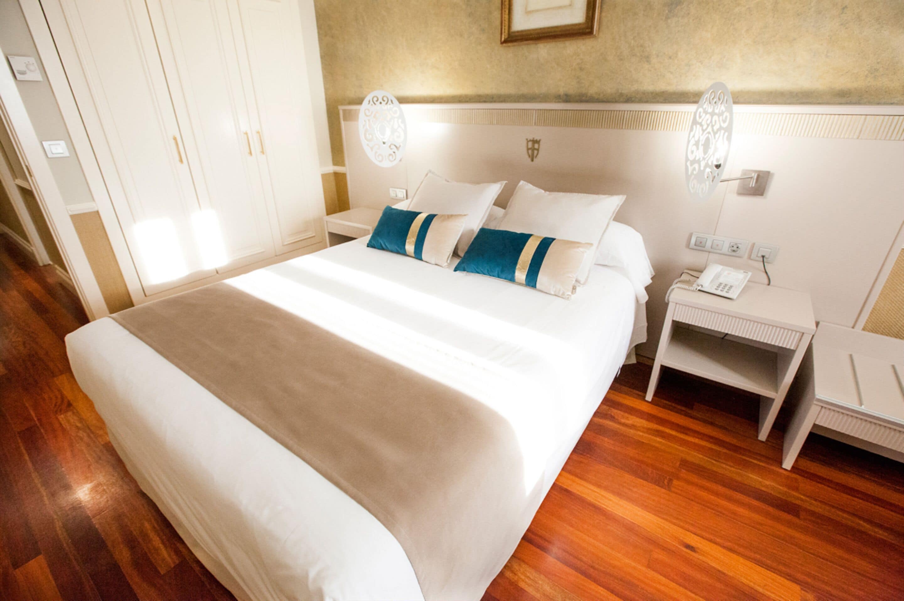 Una habitación de hotel ordenada con una cama grande, mesitas de noche, un armario y un teléfono.