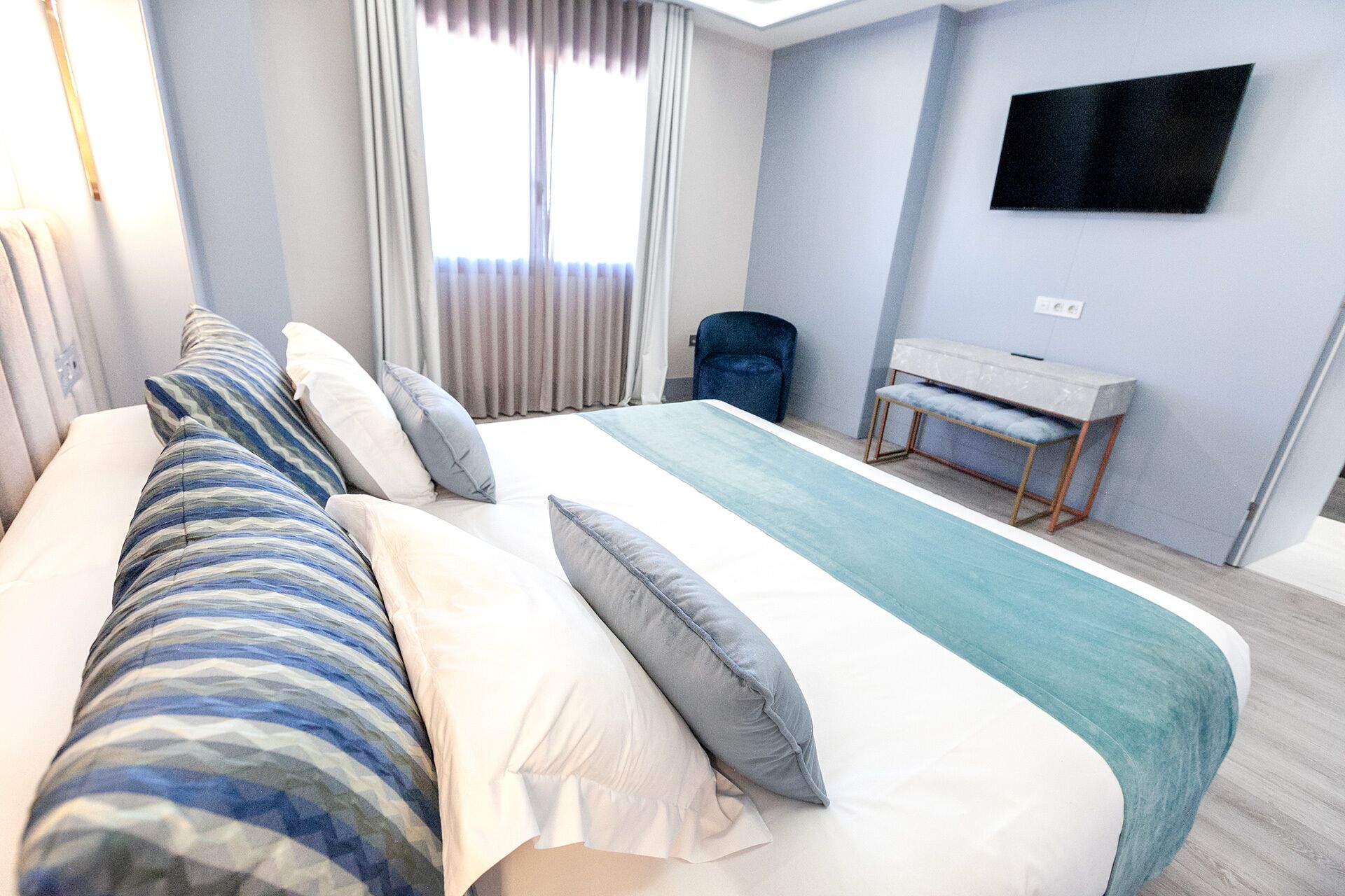 Una habitación de hotel moderna con una cama grande, un escritorio y un televisor en la pared.