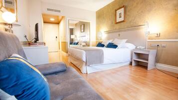 Een hotelkamer met een bed, een slaapbank, een bureau en een spiegel.