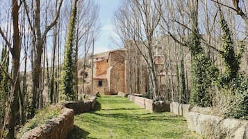 Ein gepflasterter Weg führt zu einem rustikalen Steinhaus, umgeben von kahlen Bäumen.