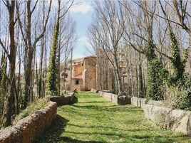 Un sendero de piedra que conduce a un edificio rústico de piedra, rodeado de árboles sin hojas.