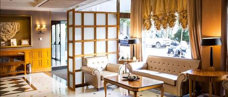 Un moderno vestíbulo de hotel con un conjunto de sofás, una mesa de centro y un separador decorativo.