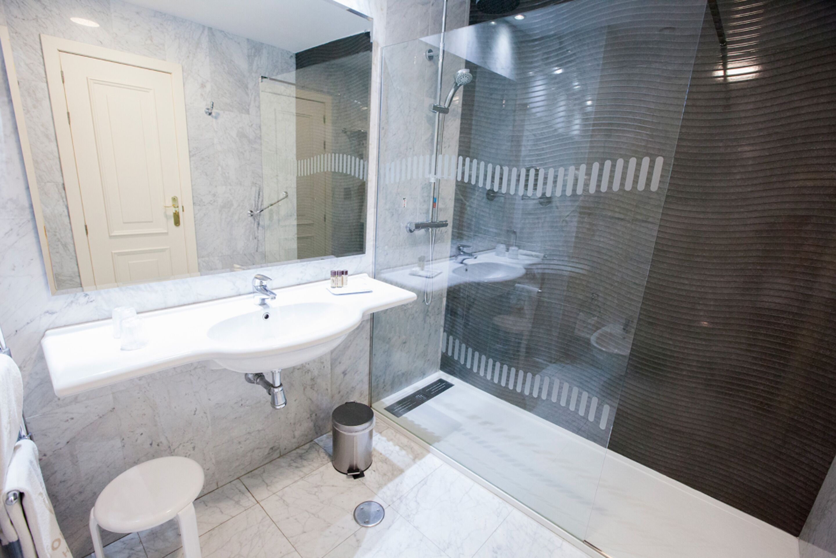 Ein modernes Badezimmer mit großem Spiegel, zwei Waschbecken, einer Dusche und einer Toilette.
