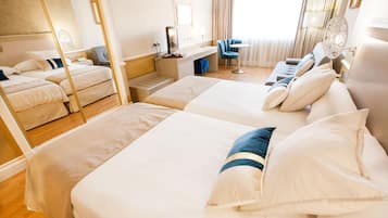 A hotel room with two beds, a desk, a chair, and a small table.