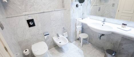 Un baño moderno con suelo de mármol, un lavabo blanco, un bidé y un inodoro.