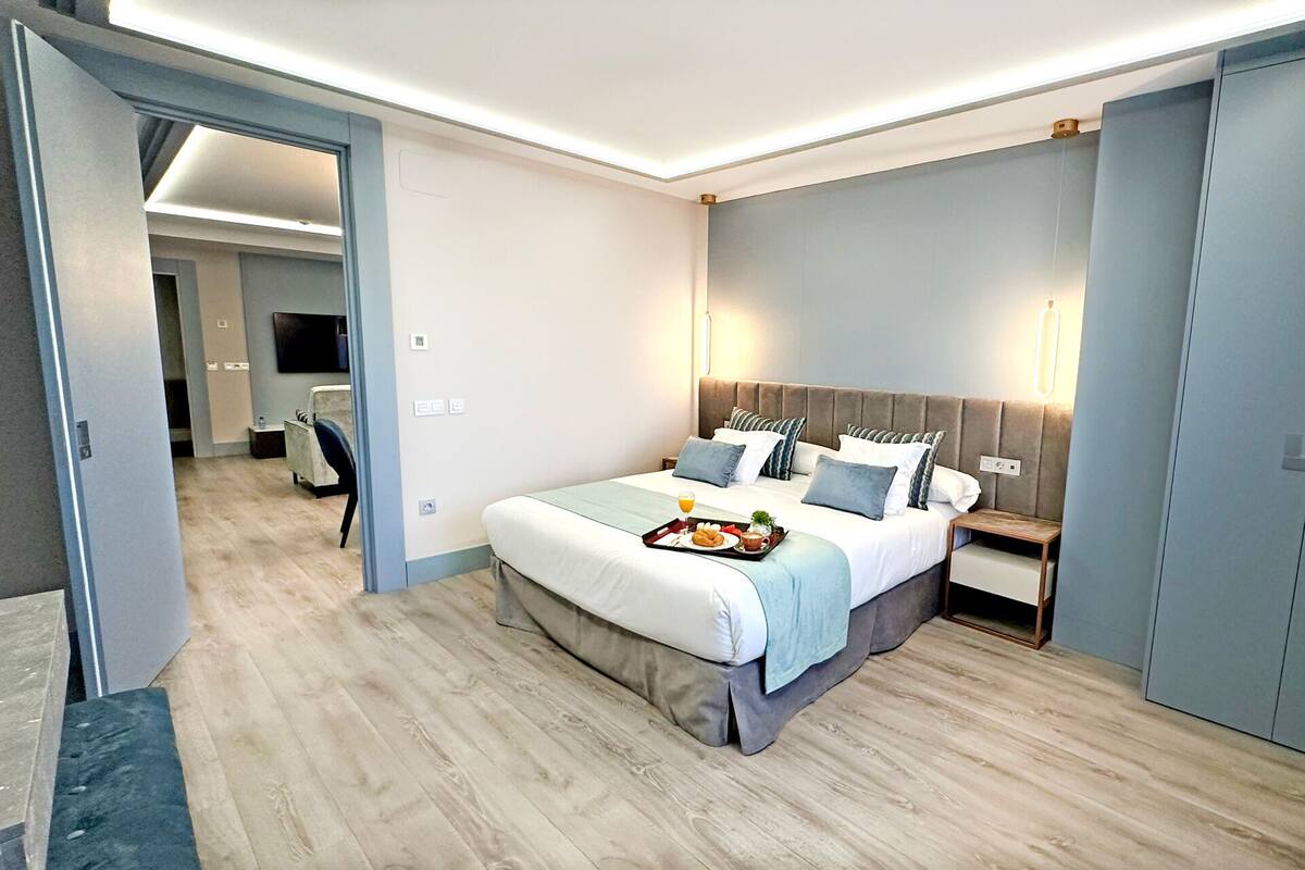 A modern hotel room with a large bed, bedside tables, a desk, and a chair.