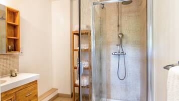 A modern bathroom with a glass-enclosed shower, a wooden vanity, and a tiled shower wall.