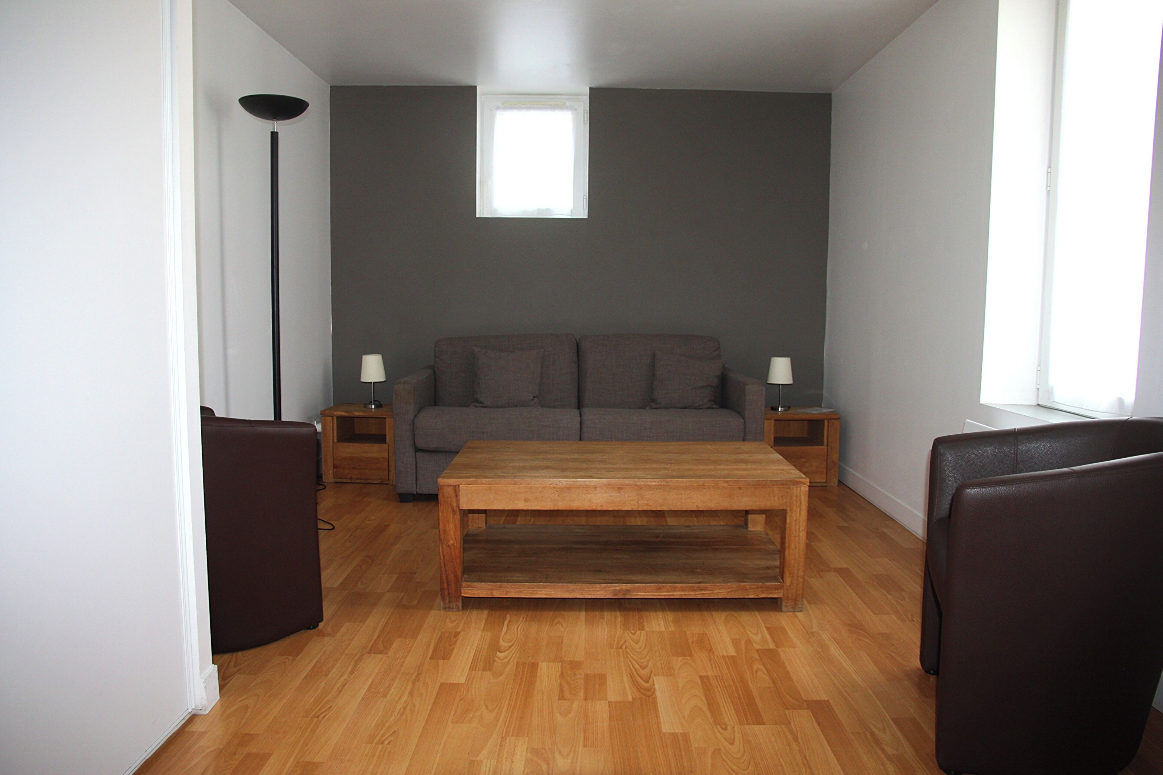 Ein Wohnzimmer mit einer Couch, zwei Nachttischen, einem Couchtisch und einer Stehlampe.