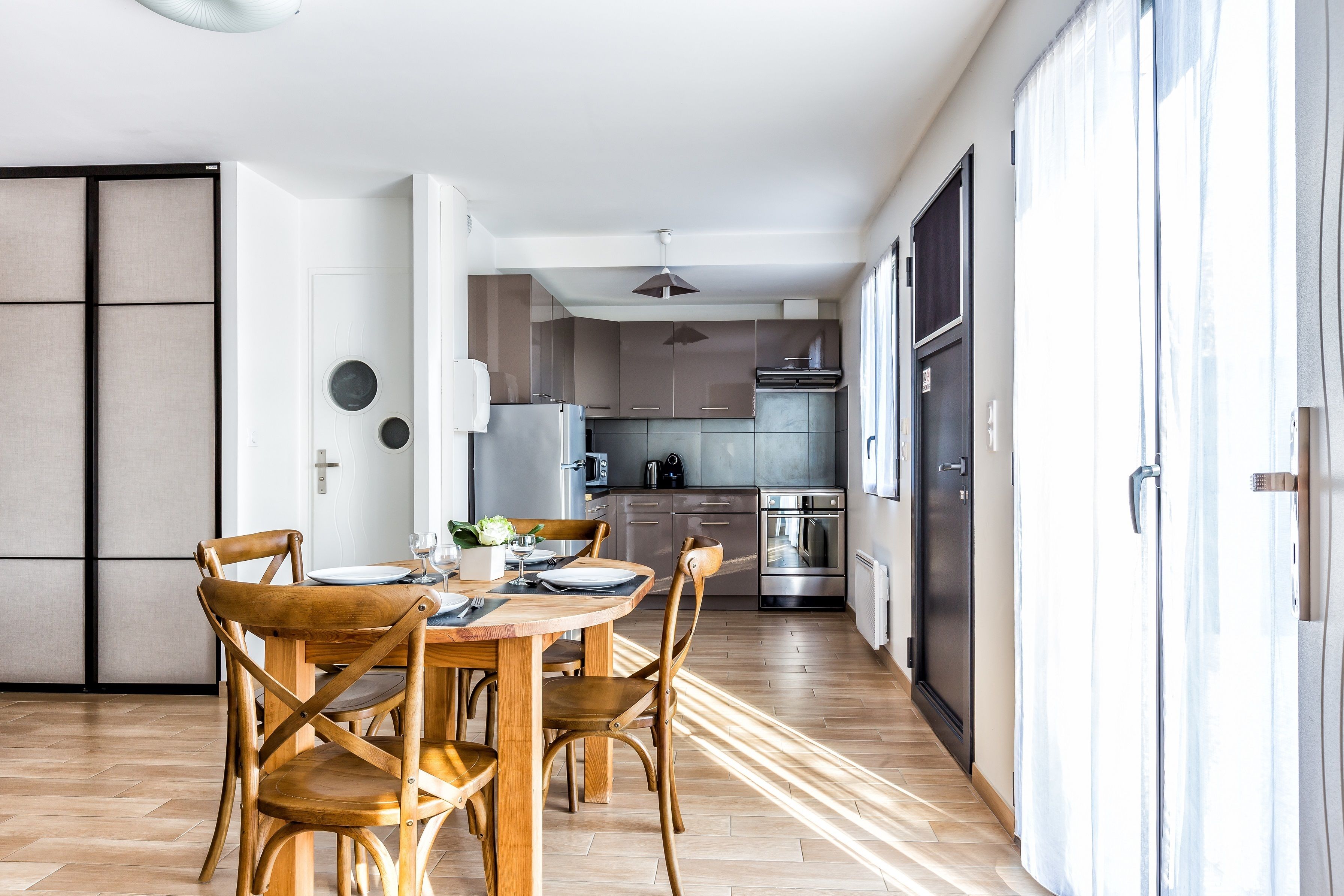 Une cuisine moderne avec un coin repas, un plancher en bois et une porte coulissante donnant sur un balcon.