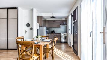 Une cuisine moderne avec un coin repas, un plancher en bois et une porte coulissante donnant sur un balcon.