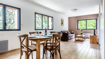A spacious living area with a dining table, chairs, and a sofa.