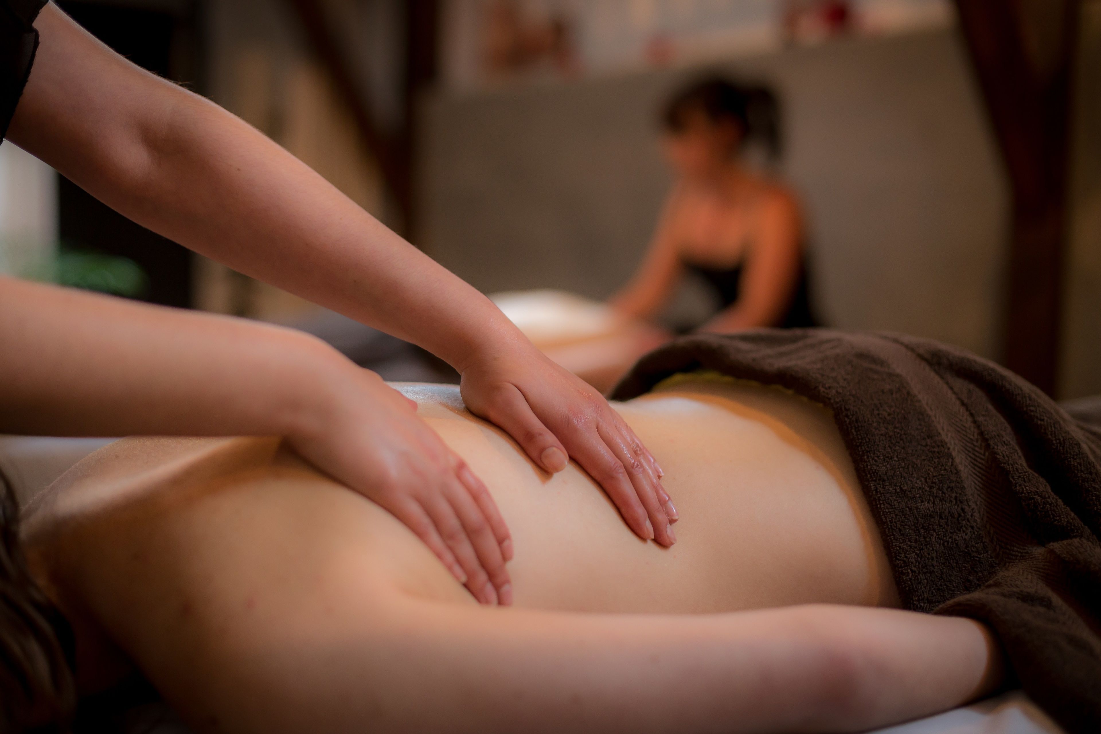 A massage therapy session in progress with a focus on the therapist's hands and the client's back.