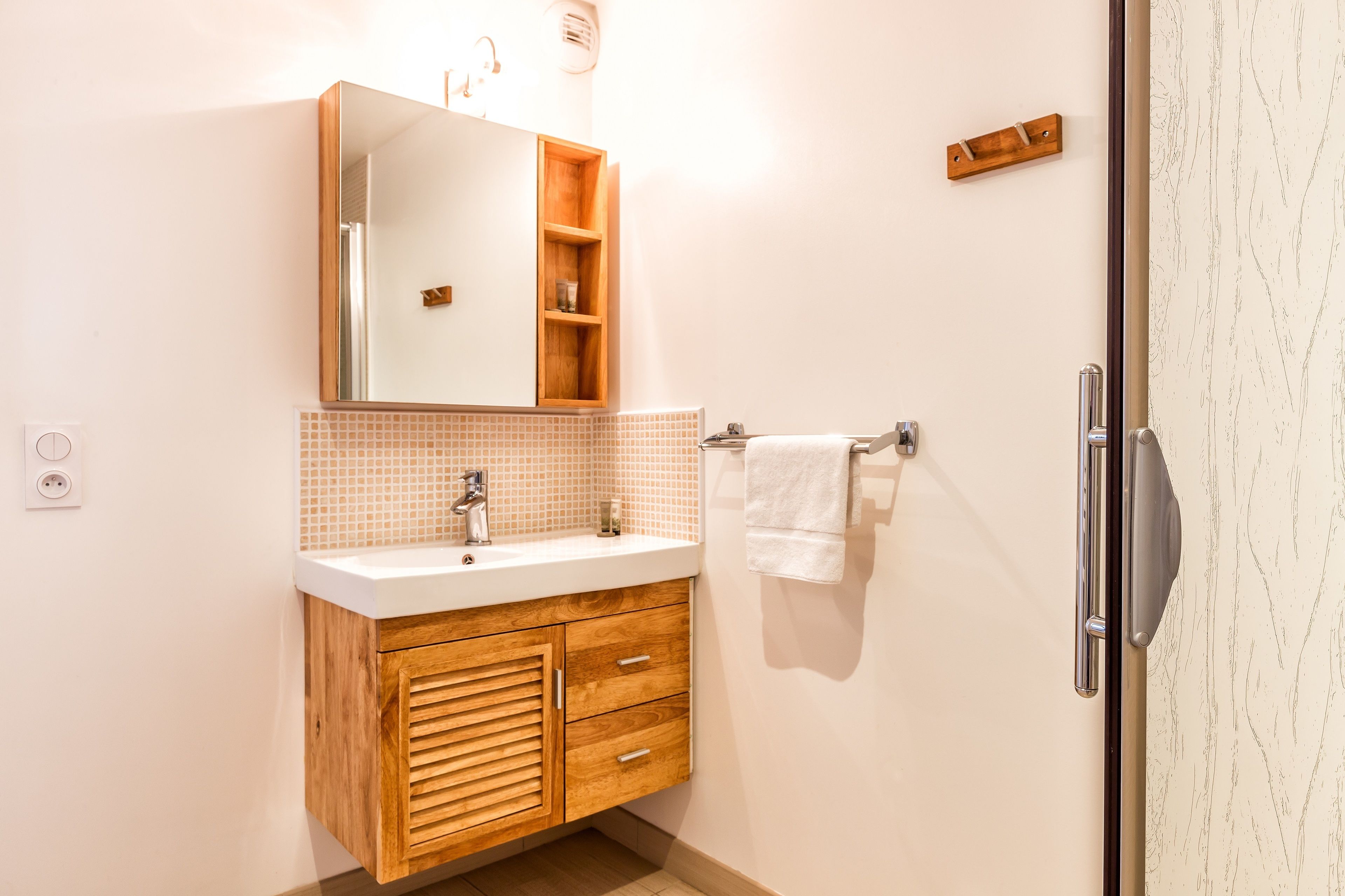 Un baño con tocador de madera, un espejo, un lavabo y un perchero para toallas.