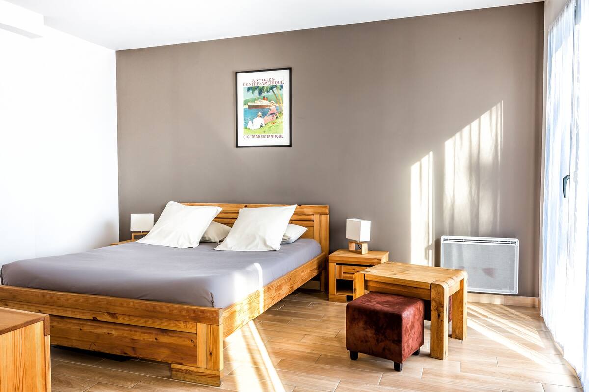 A bedroom with a wooden bed, bedside tables, a small wooden bench, and a radiator.