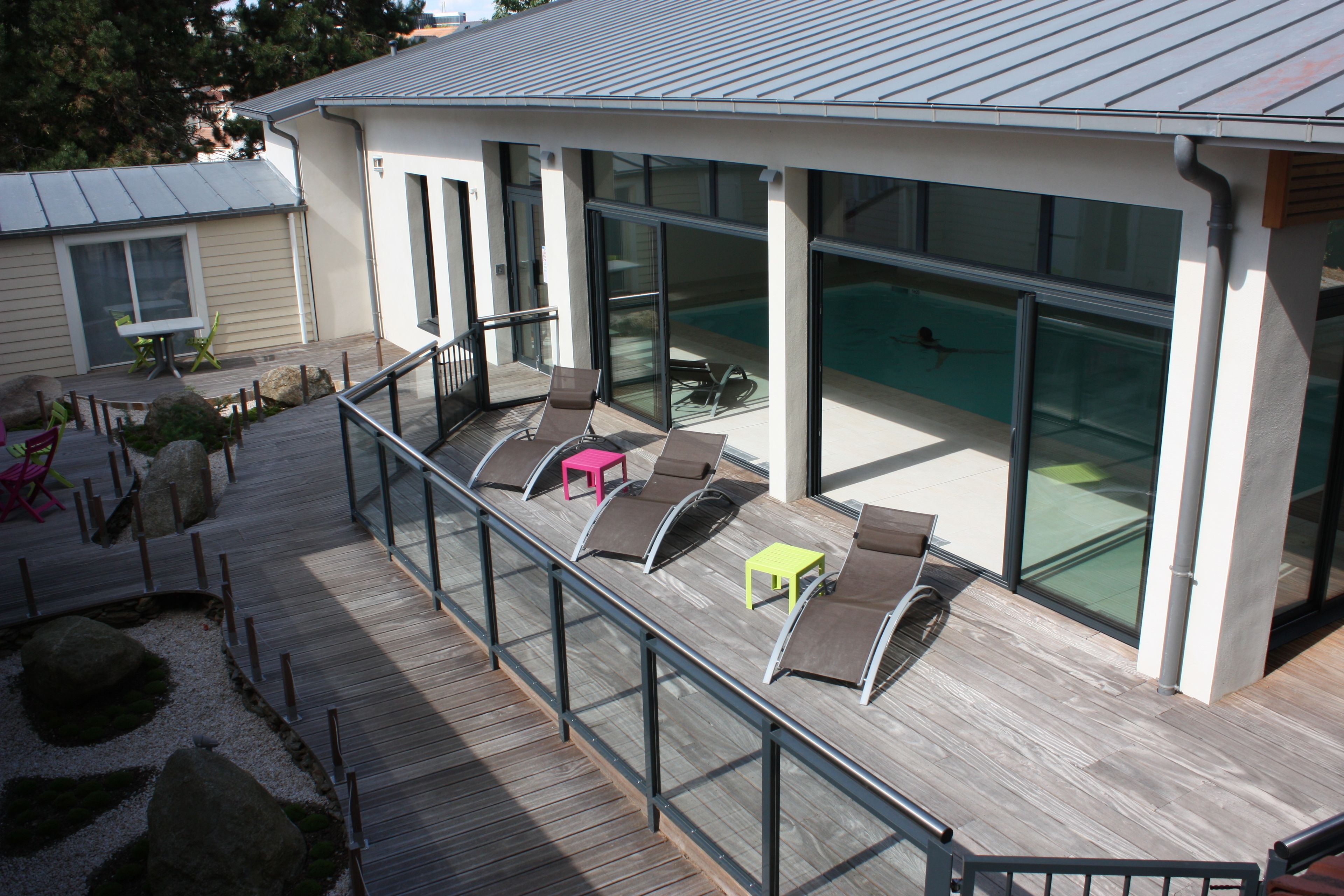 Een modern terras buiten met lounge stoelen en een kleine tafel, met uitzicht op een zwembad.