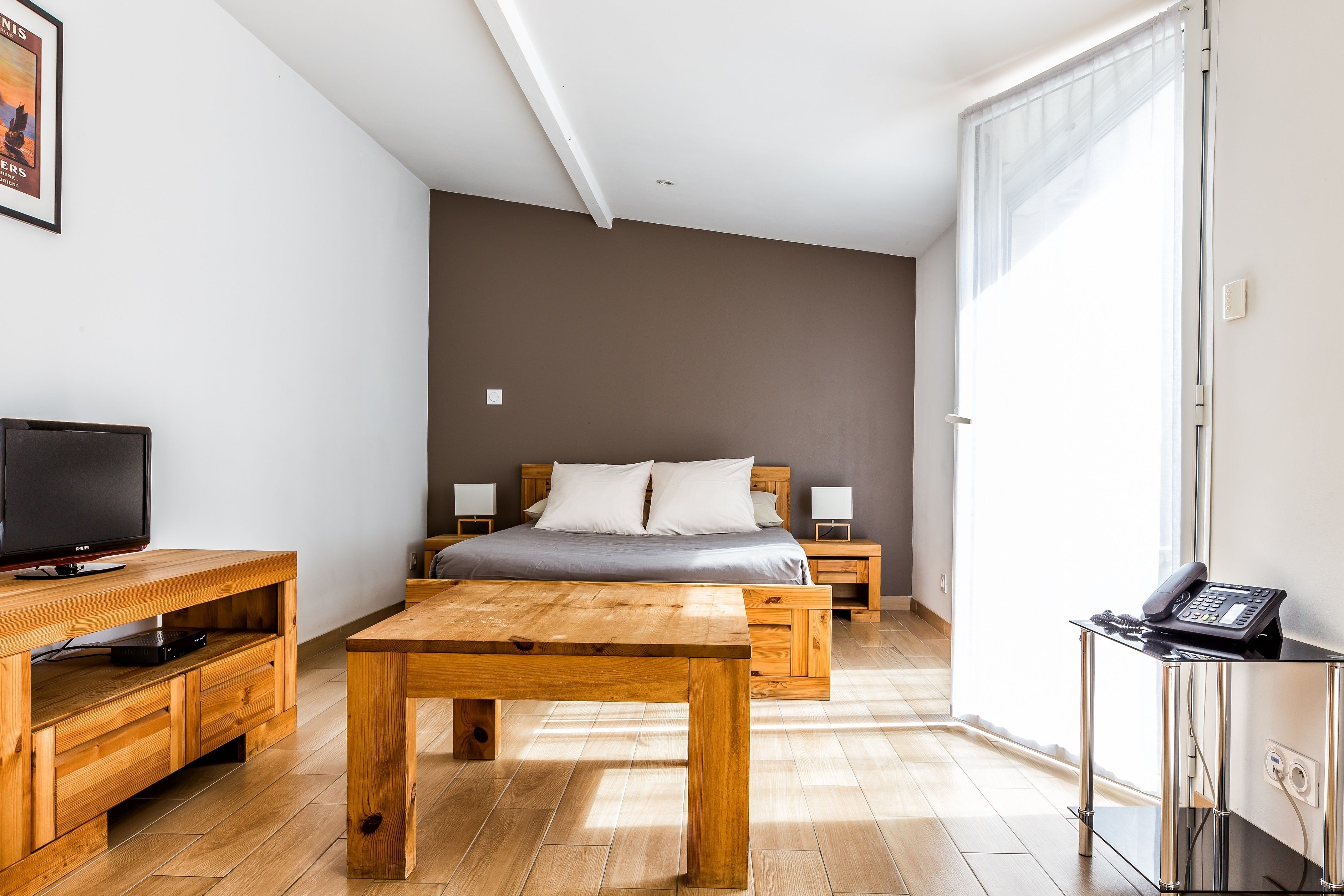 Une chambre à coucher moderne avec un lit en bois, des tables de chevet, une télévision et un bureau.