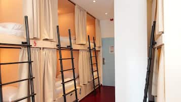A dormitory room with bunk beds, numbered beds, and a door to another room.