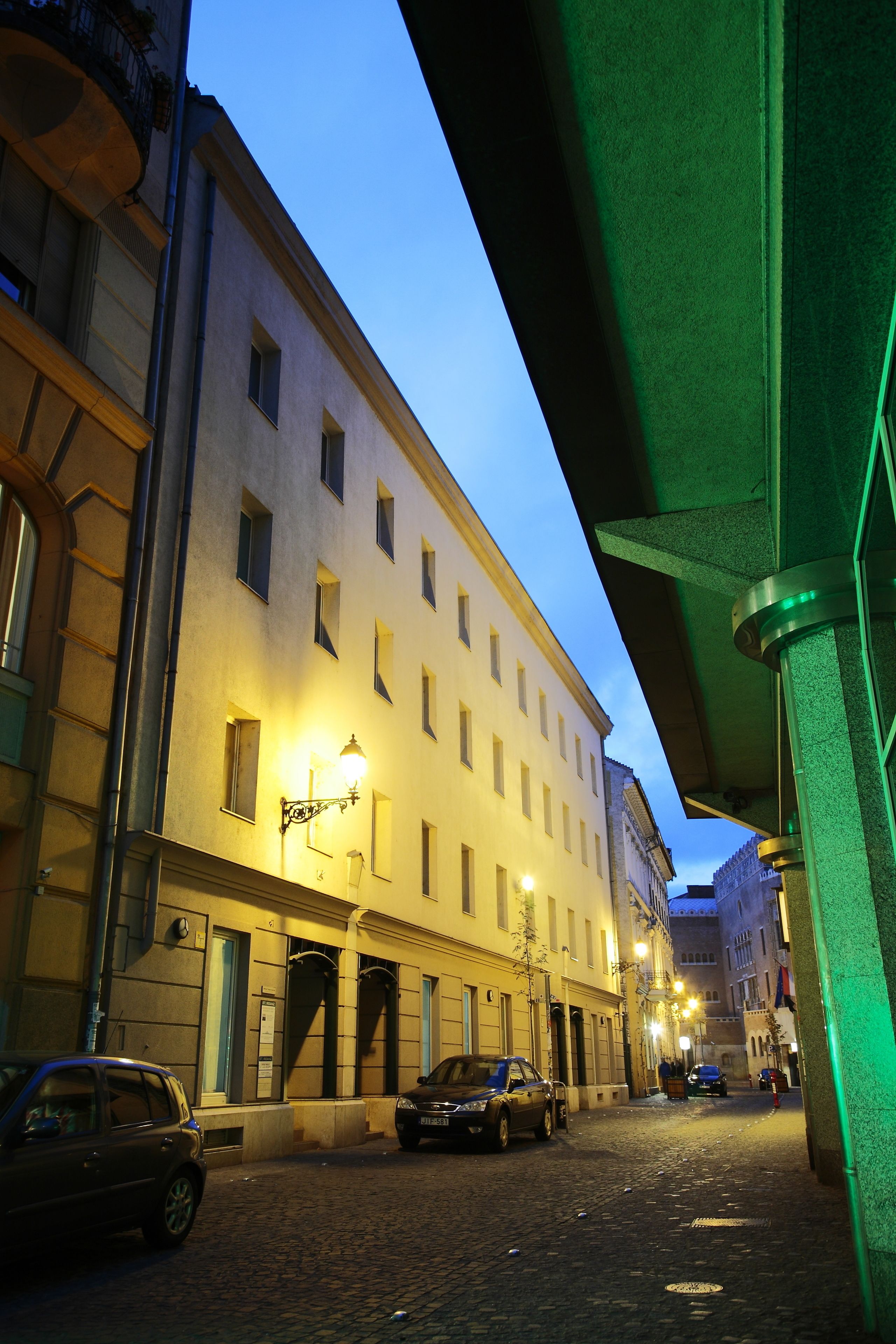 A narrow cobblestone street with buildings on either side, under an overpass.