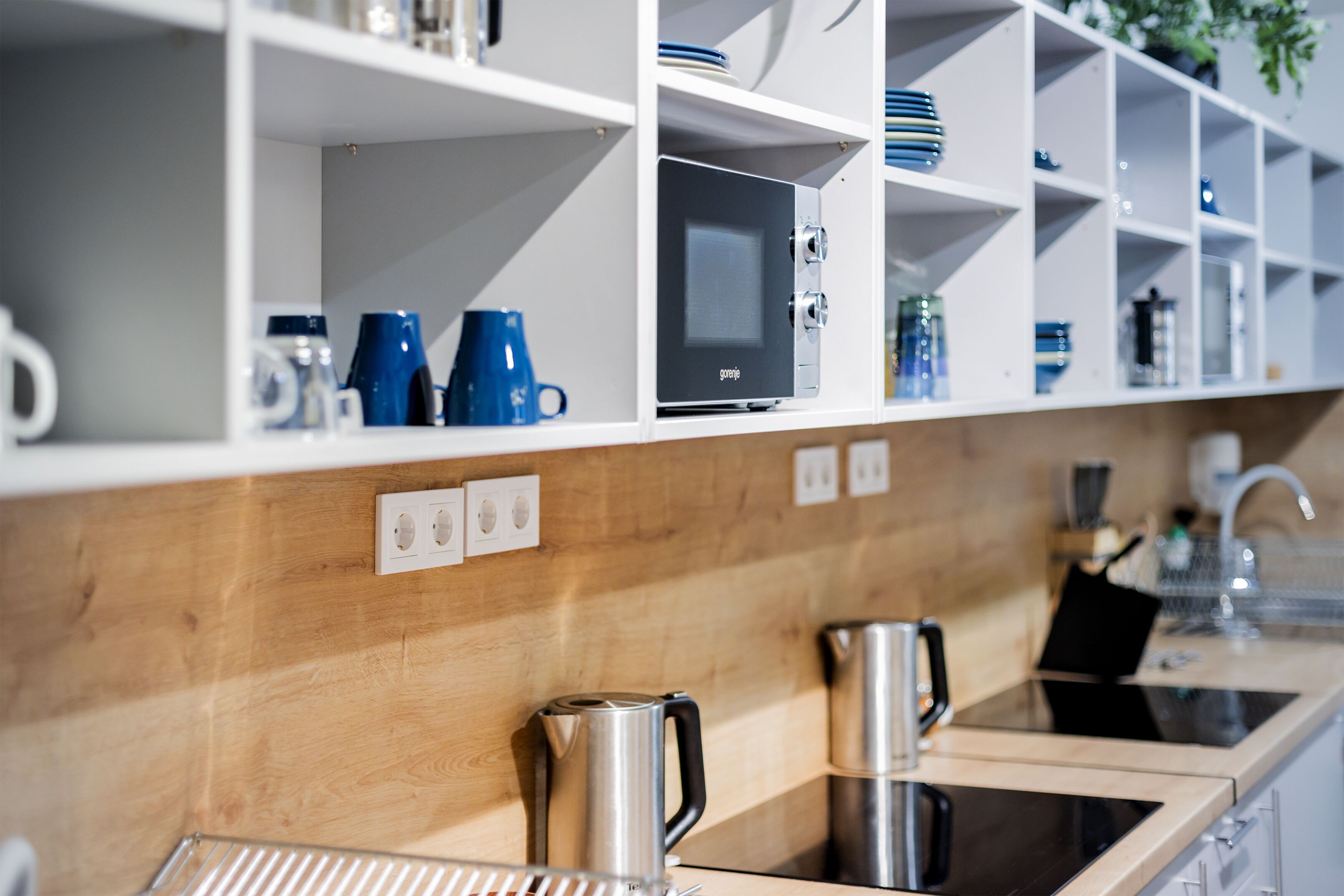 A kitchen with white shelves, a wooden countertop, and stainless steel appliances.
