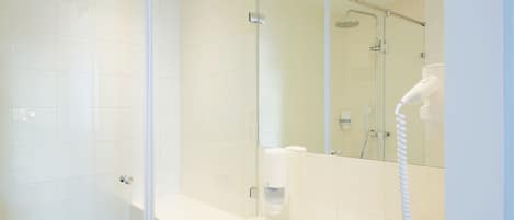 Un baño moderno con cabina de ducha de vidrio, lavamanos blanco y ducha de mano.