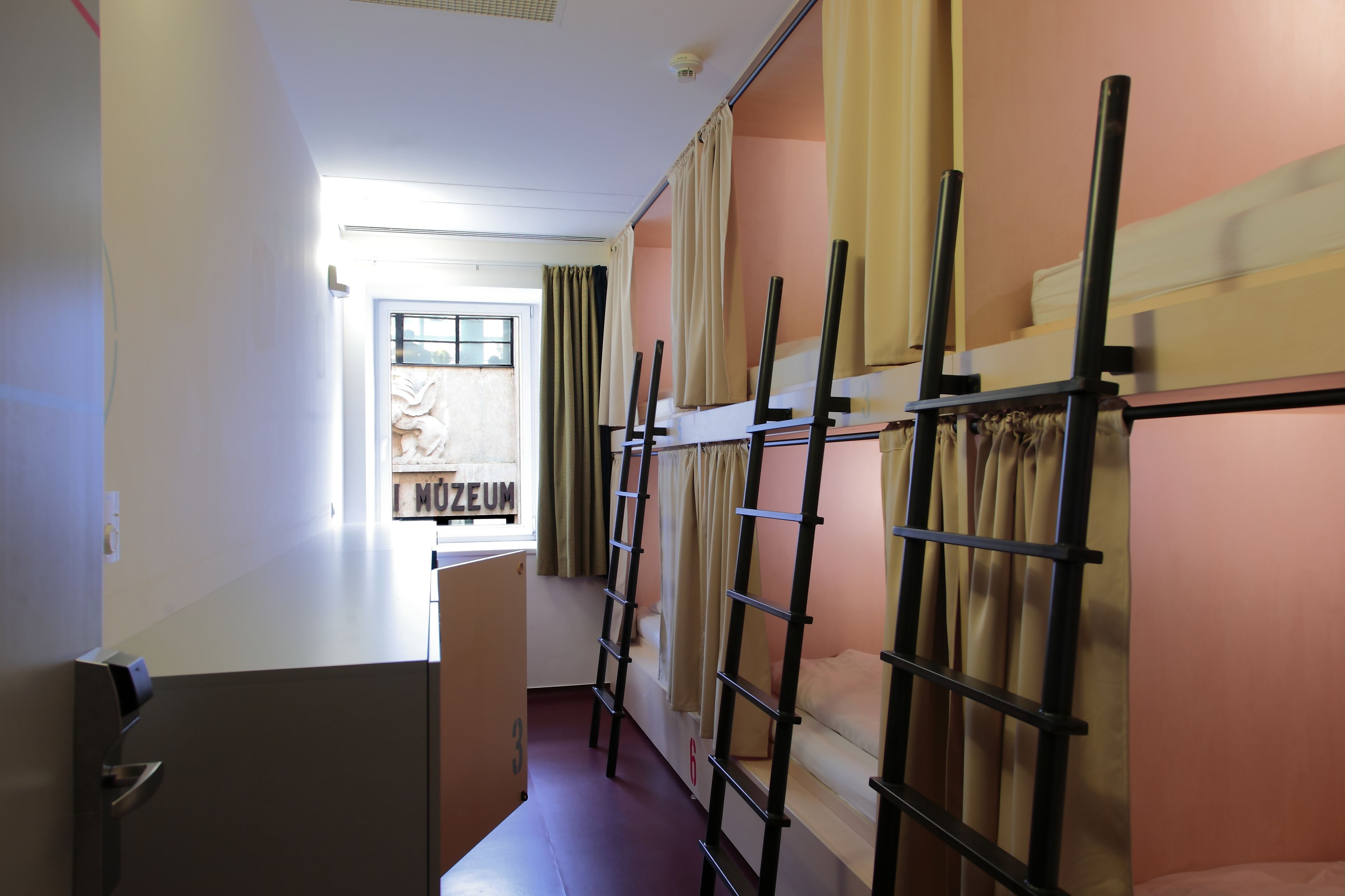 Un dormitorio con literas, una ventana con cortinas y una puerta que da a un pasillo.