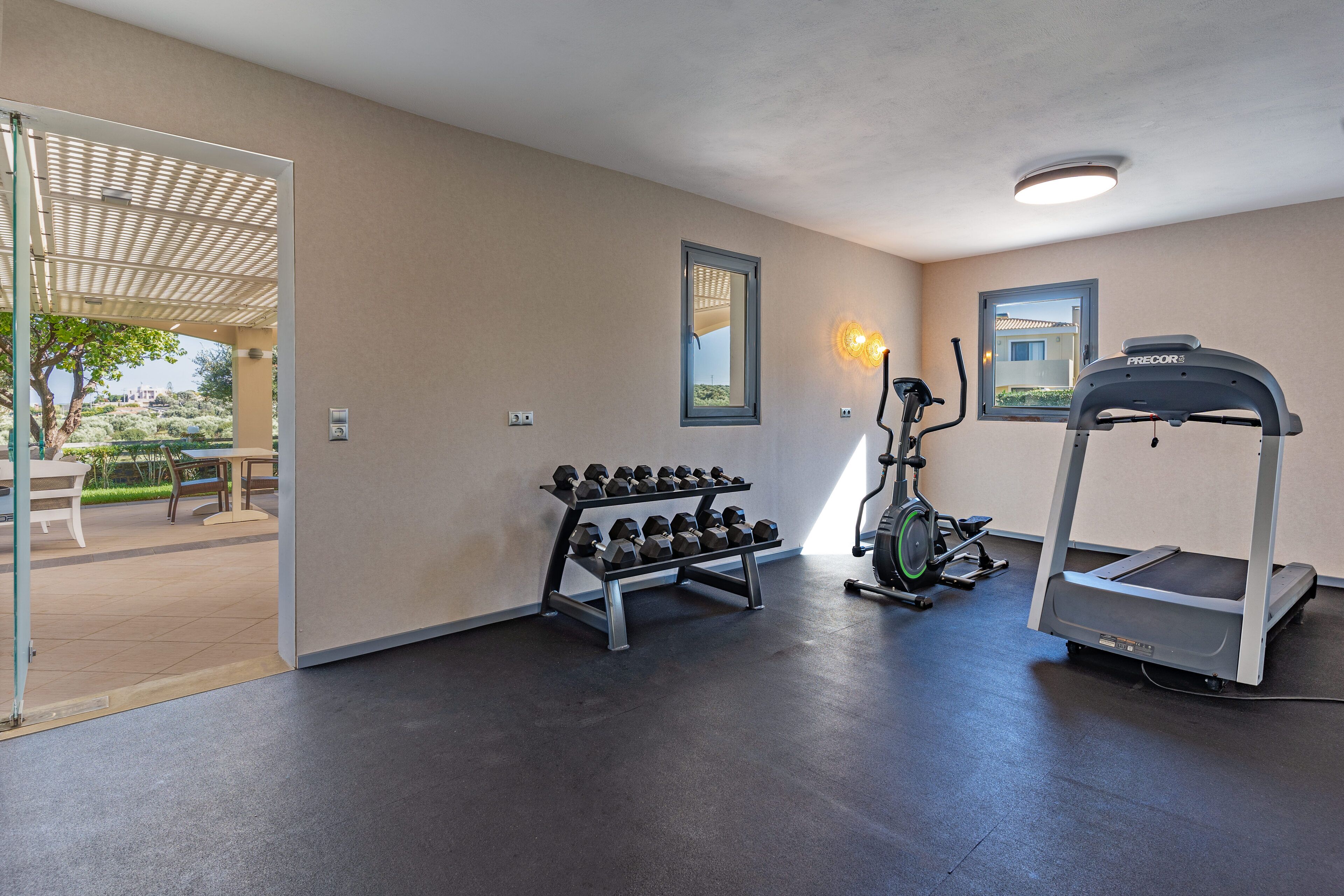 Ein Fitnessraum mit Laufband, Hanteln und Trainingsgeräten.