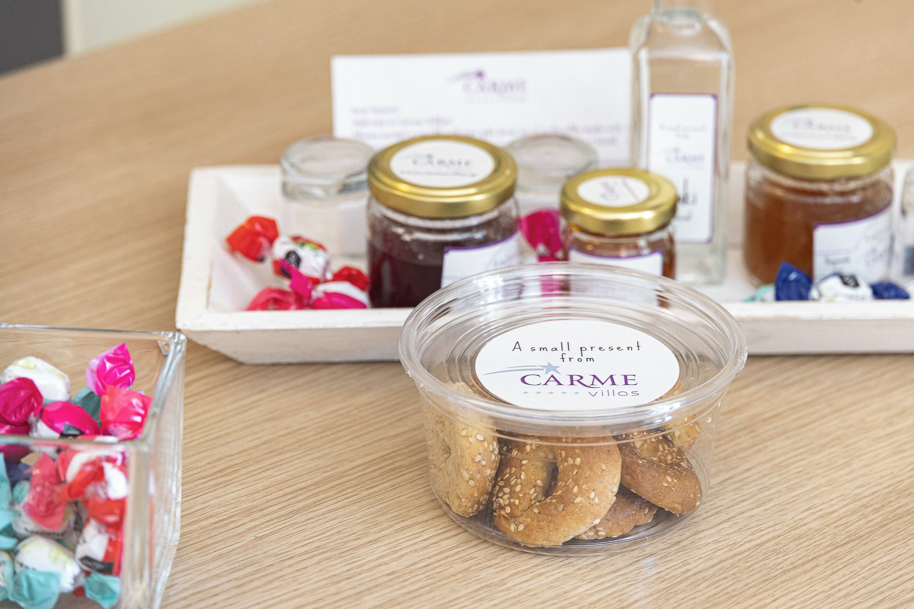 A tray with jars of jam, a container of cookies, and a glass with colorful candies.