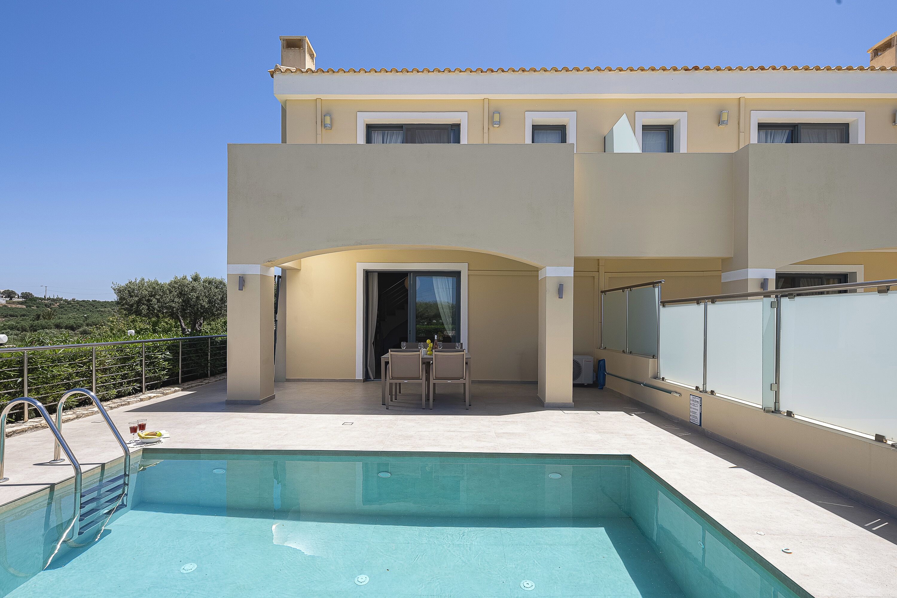 Une piscine avec des chaises longues et une table, un patio couvert et un bâtiment doté d’un toit en tuiles.