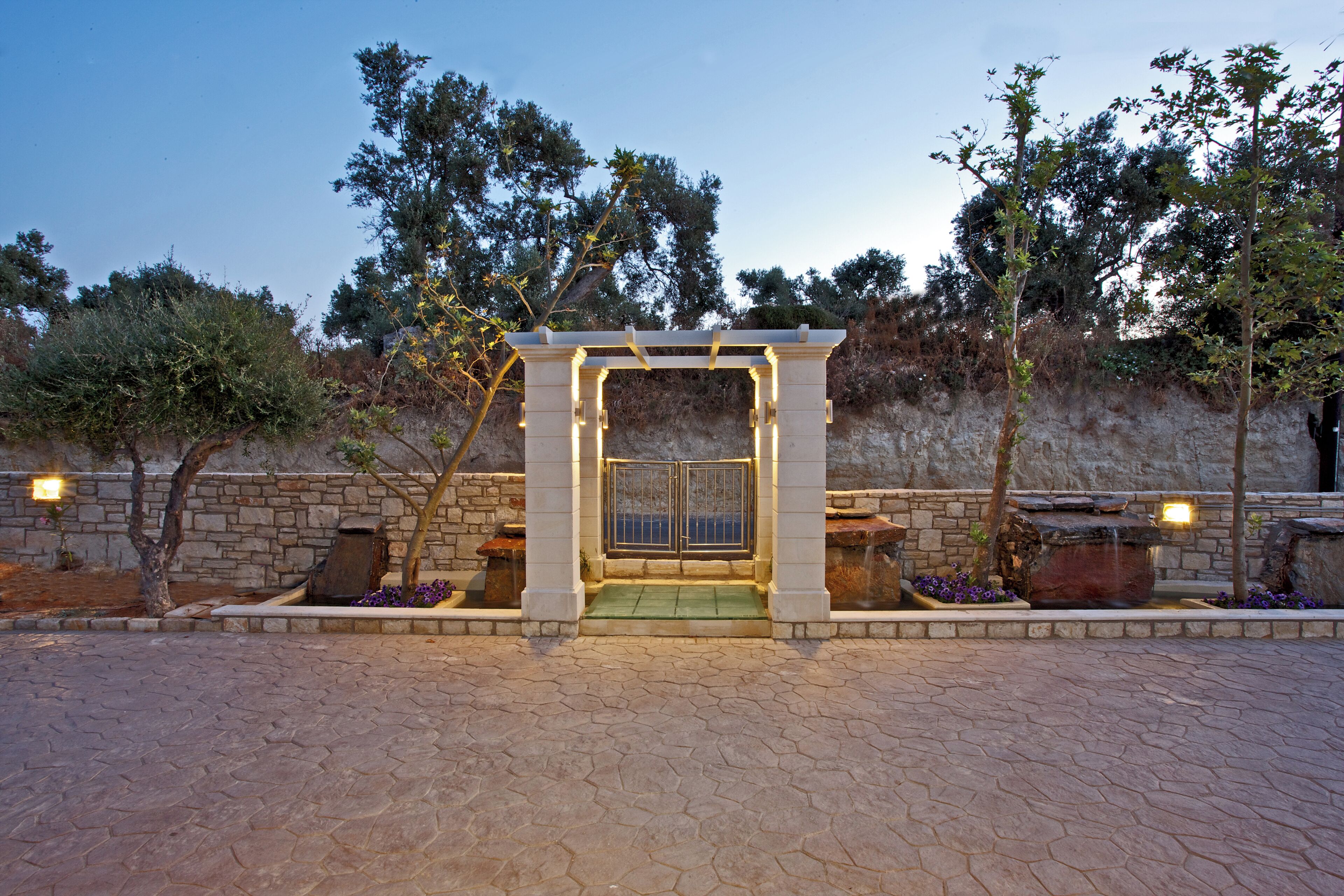 A stone archway with a door, surrounded by stone walls and trees.