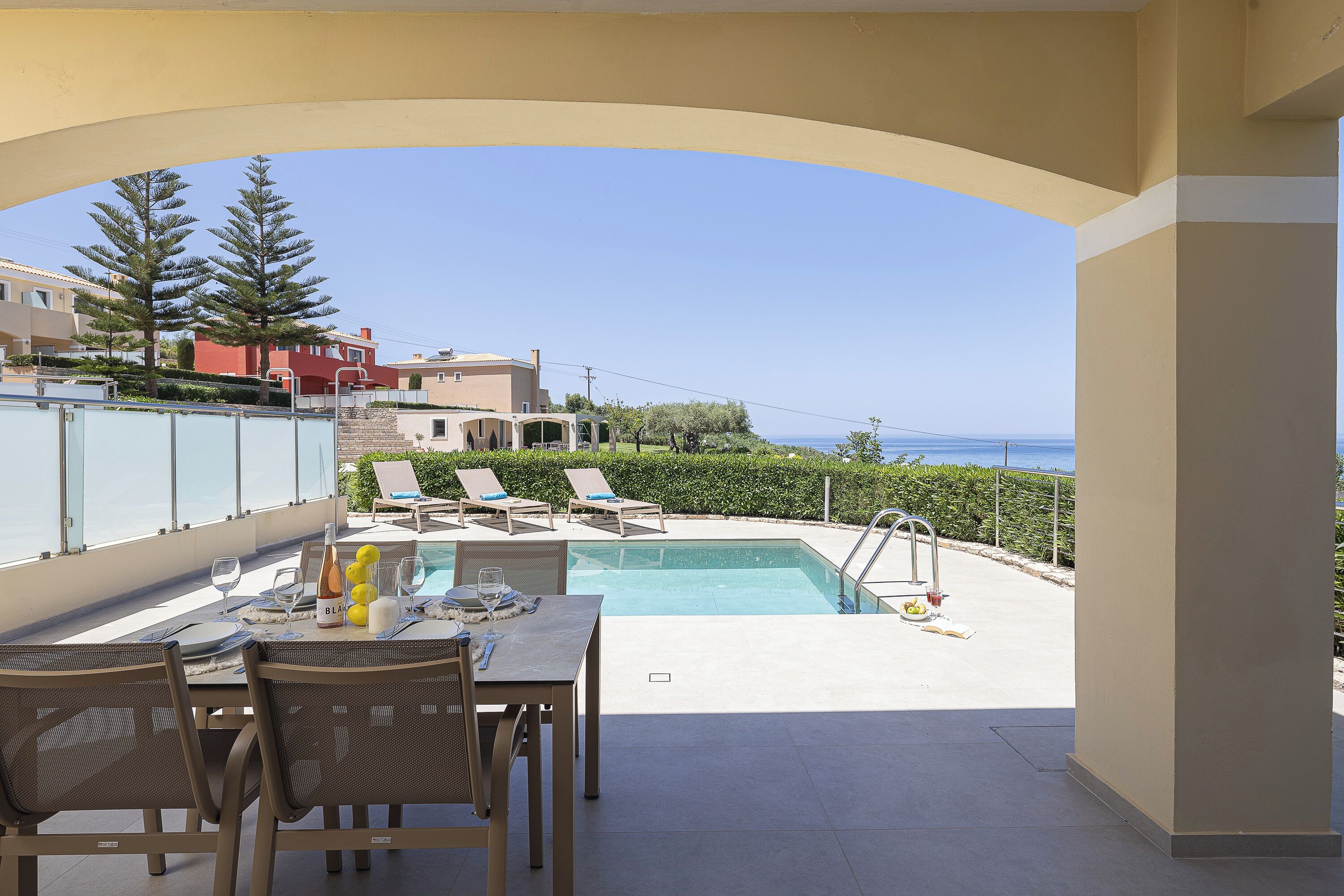 Ein Poolbereich mit Tisch für zwei Personen, einem Pool und Blick aufs Meer.
