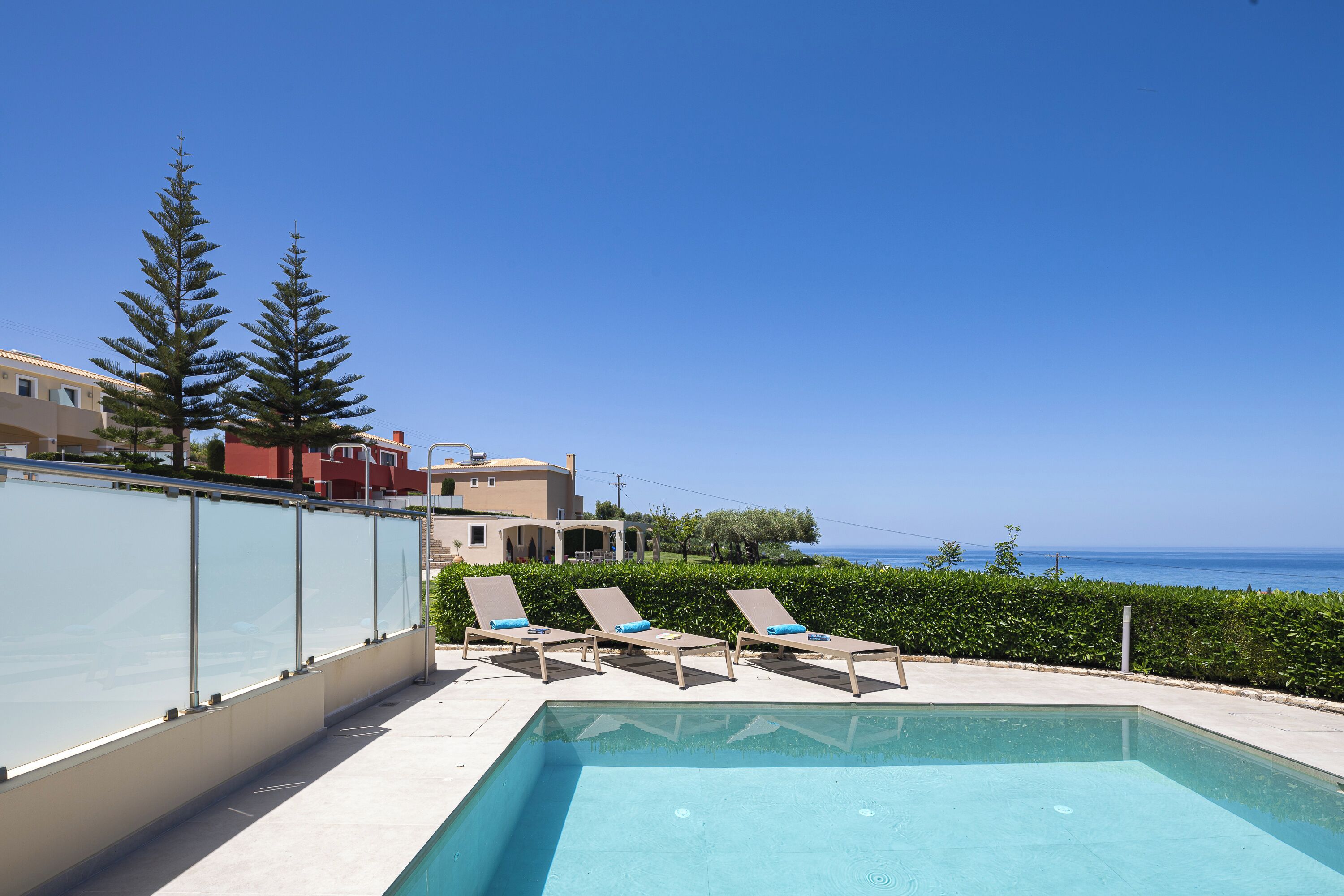 Zona de piscina con sillones de descanso y vistas al mar.