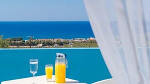 Una mesa con dos vasos y una jarra de jugo de naranja, con vista a un pueblo costero.