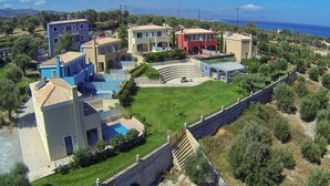 Zona residencial costera con varias casas, una piscina y un muro de piedra.