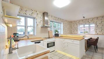 A modern kitchen with white cabinetry, a built-in oven, a microwave, and a large window providing natural light.