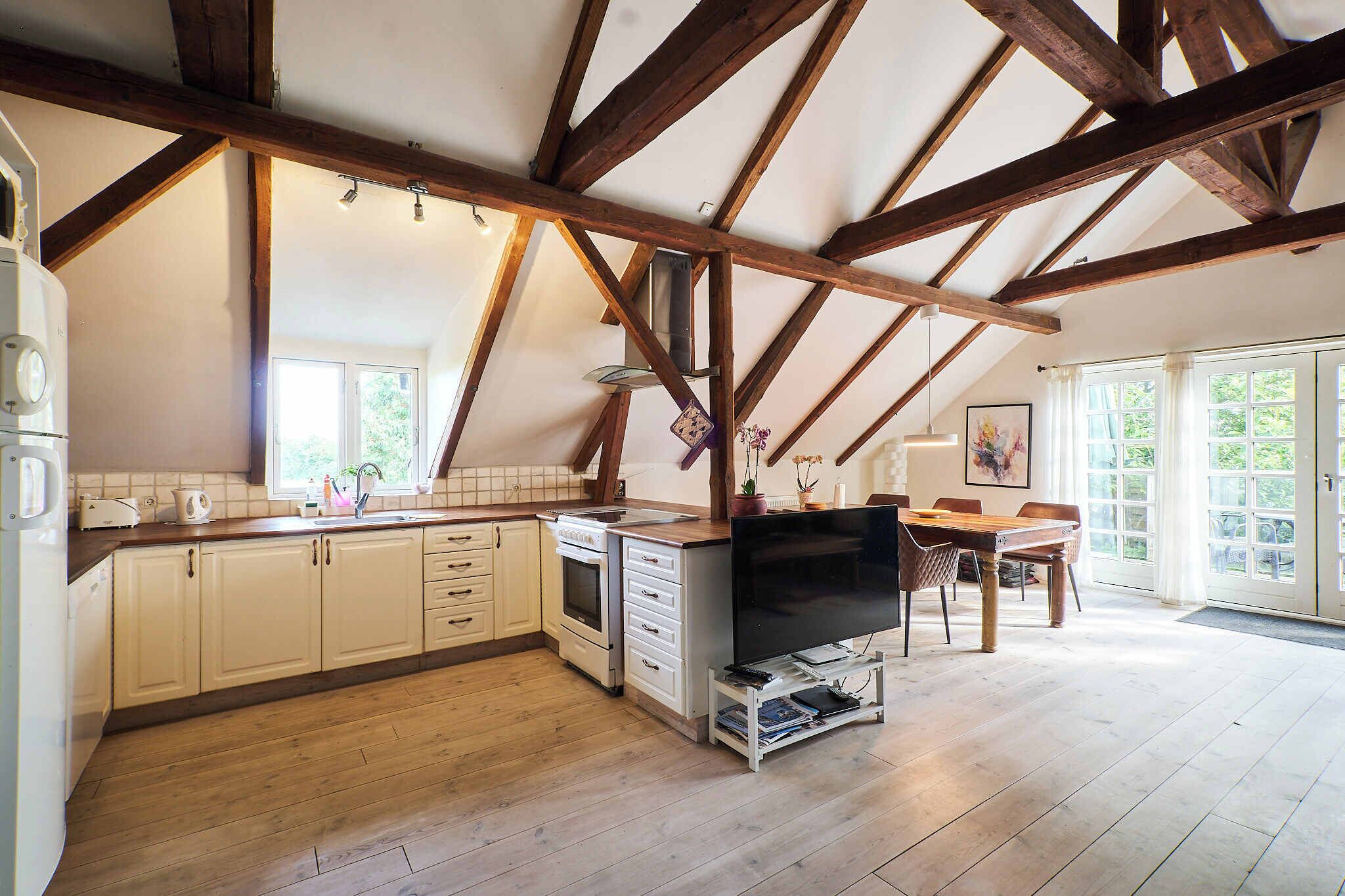 A kitchen with wooden beams, a dining area, and a large window.
