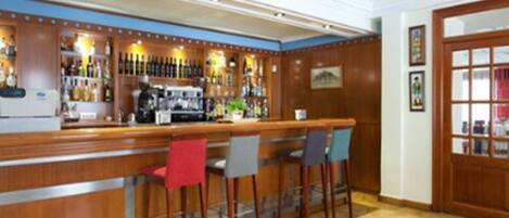 A bar area with a counter, bar stools, and a variety of bottles and glasses on shelves.