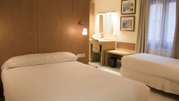 A hotel room with two beds, a desk, a chair, a mirror, and a window with curtains.