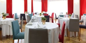 Formal dining area with round tables, comfortable seating, and lush greenery.