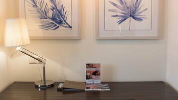 A modern desk with a lamp, framed artwork, and a chair.