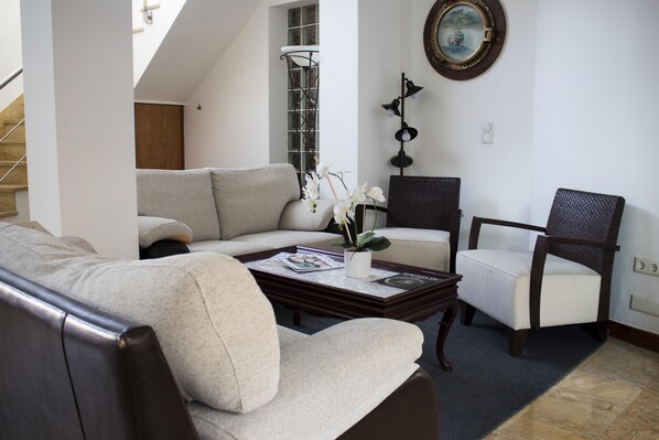 Sala de estar con sofá, sillón, mesa de centro y objetos decorativos.